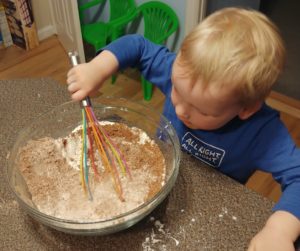 child mixes contents in bowl